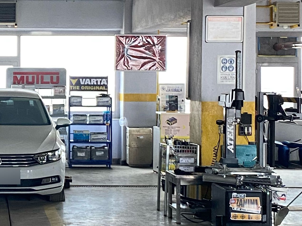 Servis şubesinde Mutlu ve Varta akü rafı; önde lastik sökme-takma makinesi