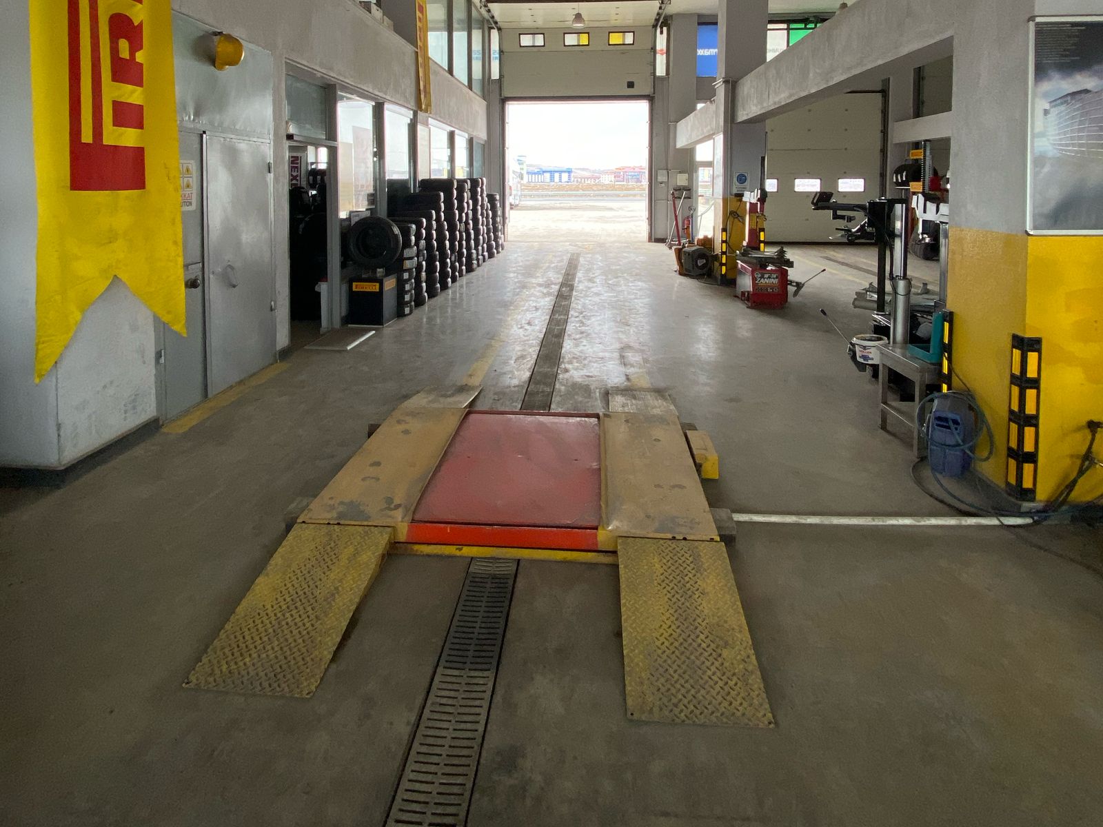 Servis şubesinin salonu: önde kaldırma platformu, sağda lastik sökme-takma makineleri, solda lastik istifi